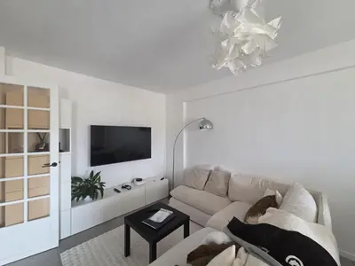 a white living room with a couch and a tv at Spacieux 4 pièces - Balcon - Parking - FC in Saint-Laurent-du-Var