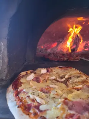 a pizza is in front of a fire oven at Studio de la Villa Thérèse, Piscine & Jardin in Saint-Laurent-du-Var
