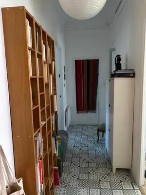 a hallway with a room with bookshelves and a refrigerator at 3 pièces lumineuses, 3 nuitées minimum in Nice