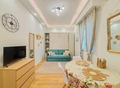 a living room with a table and a tv at Cherie in Nice in Nice