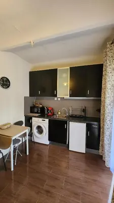 a kitchen with black cabinets and a sink and a table at Nice 2-room apartment off the beach in Nice