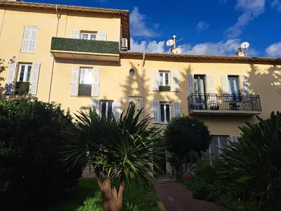 a building with a palm tree in front of it at Bel appartement proche de la mer et de la gare La Mascotte in Beaulieu-sur-Mer