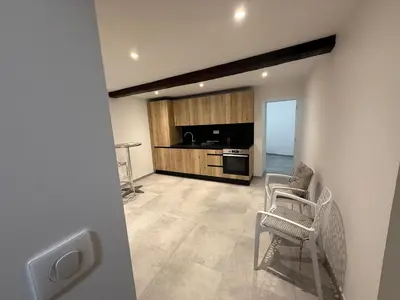 a living room with a couch and chairs and a kitchen at Bel appartement proche de la mer et de la gare La Mascotte in Beaulieu-sur-Mer
