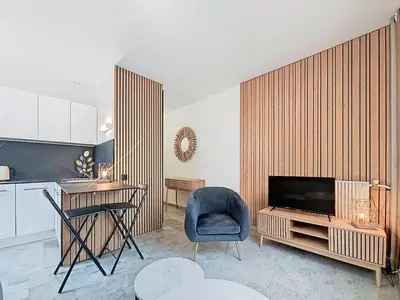 a living room with a television and a blue chair at Beach Studio on Cagnes sea front in Cagnes-sur-Mer
