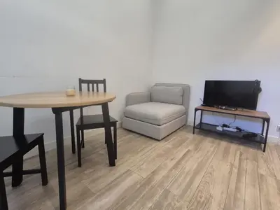 a living room with a table and a chair and a television at petit appart cozy in Nice