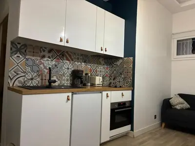 a kitchen with white cabinets and a tile wall at petit appart cozy in Nice