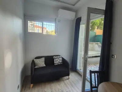 a living room with a black chair and a mirror at petit appart cozy in Nice