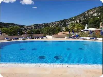a large swimming pool with a mountain in the background at Mer et Soleil in Villefranche-sur-Mer