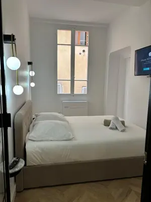 a bed in a white room with a window at Luxueux Logement à 2 pas de la mer, Vieille ville in Nice
