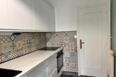 a kitchen with white cabinets and tiles on the wall at Studio with veranda 5min walk to the beach in Nice