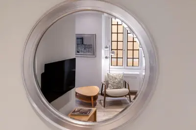 a mirror reflecting a living room with a chair and a television at Authentic Nice Old Town, separate bedroom, AC in Nice