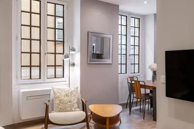 a living room with a tv and a table with chairs at Authentic Nice Old Town, separate bedroom, AC in Nice