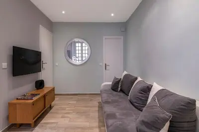 a living room with a gray couch and a tv at Authentic Nice Old Town, separate bedroom, AC in Nice