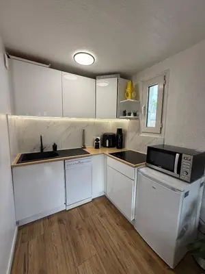 a small kitchen with white cabinets and a microwave at AZUR DELUXE Nice in Nice