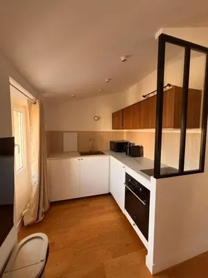 a kitchen with white cabinets and a black oven at Cozy & Lumineux Studio proche mer in Nice