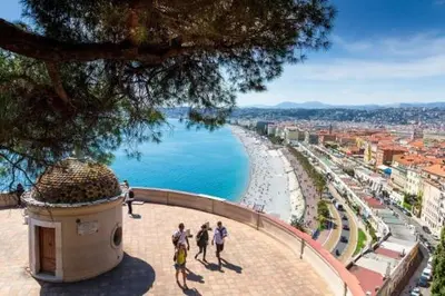 a group of people walking on a sidewalk next to a beach at Résidence So Amata , à deux pas du Port de Nice in Nice