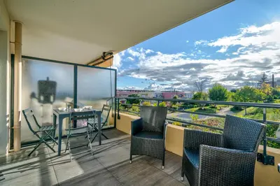 a balcony with chairs and a table with a view at Superbe 2 pièces - Piscine et garage in Nice