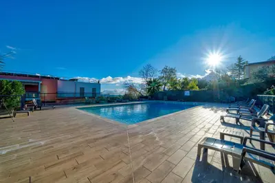 a swimming pool with chairs on a patio at Superbe 2 pièces - Piscine et garage in Nice