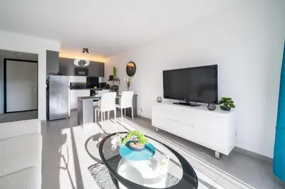 a living room with a glass table and a tv at Superbe 2 pièces - Piscine et garage in Nice