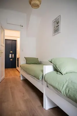 two beds in a room with white walls and wood floors at Appartement-Suite neuf - 2 chambres - 1 min mer in Nice