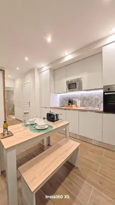 a kitchen with white cabinets and a wooden table at New T2 Nice Jean Médecin - L'Hacienda de Bali in Nice