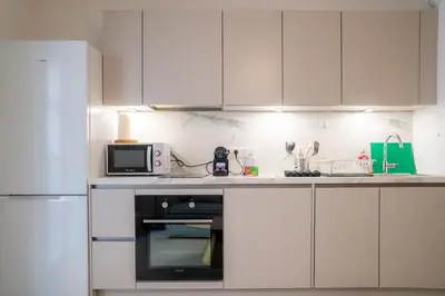 a kitchen with white cabinets and a black oven at Superbe T2 Neuf avec Terrasse Hyper Centre Nice in Nice