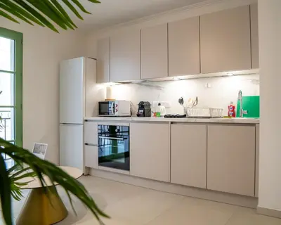 a kitchen with white cabinets and a refrigerator at Superbe T2 Neuf avec Terrasse Hyper Centre Nice in Nice