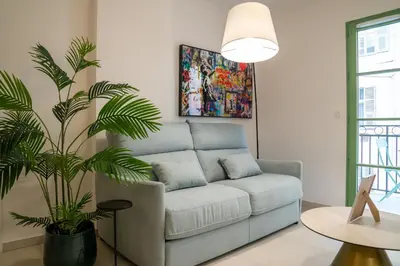 a living room with a couch and a palm tree at Superbe T2 Neuf avec Terrasse Hyper Centre Nice in Nice