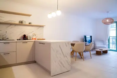 a kitchen with white cabinets and a table with chairs at T3 résidence neuve Centre-Ville 6 Couchages in Nice