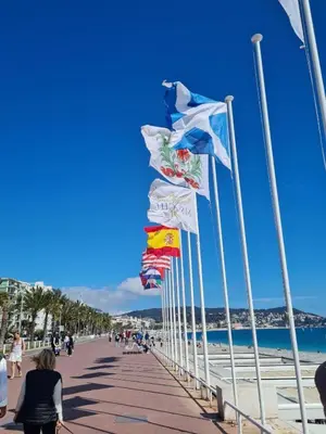 a row of flags on a boardwalk on a beach at Atelier de Lumière Nice Gambetta in Nice