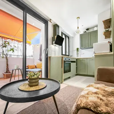 a living room with a table and a kitchen at Central, élégant & cosy in Nice