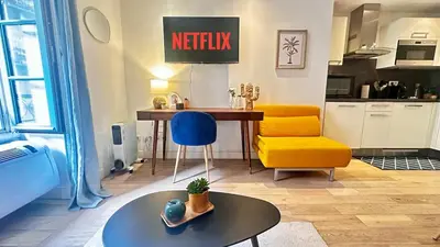 a living room with a table and a yellow chair at Studio design et lumineux près du Port de Nice in Nice