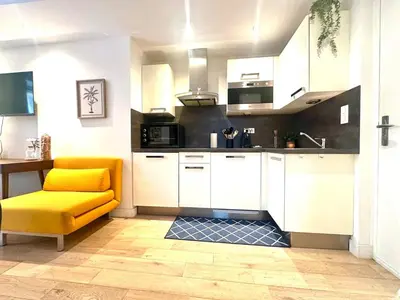 a kitchen with white cabinets and a yellow couch at Studio design et lumineux près du Port de Nice in Nice