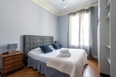 a bedroom with a bed with blue pillows and a window at La Suite Londres in Nice