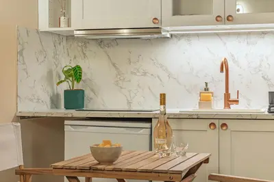 a kitchen with a wooden table with a bottle of wine at Authentic Provençal Studio in Nice