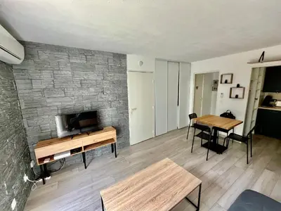 a living room with a tv and a brick wall at Le riviera bay avec parking in Saint-Laurent-du-Var