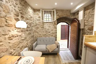 a living room with a chair in a stone wall at Studio de charme - Vieille Ville - Proche plage in Villefranche-sur-Mer