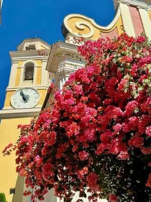 a clock tower with a large bouquet of red flowers at Studio de charme - Vieille Ville - Proche plage in Villefranche-sur-Mer