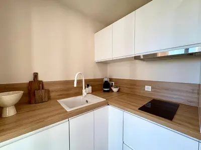 a kitchen with white cabinets and a sink at Studio cosy - Vue mer - Terrasse - Parking in Saint-Laurent-du-Var