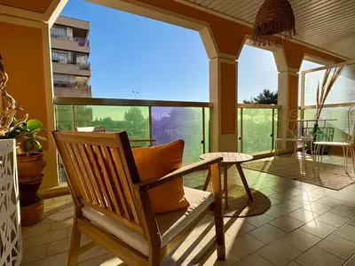 a rocking chair in a room with large windows at Studio cosy - Vue mer - Terrasse - Parking in Saint-Laurent-du-Var