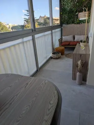 a patio with a table and a couch and windows at T2 douillet proche de Nice - Accès plage à pied in Cagnes-sur-Mer