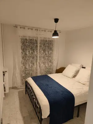 a bedroom with a bed with a blue blanket and a window at Bel appartement in Nice