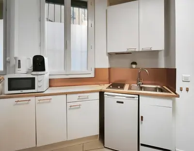 a kitchen with white cabinets and a sink and a microwave at Studio moderne et douillet au cœur de Nice in Nice