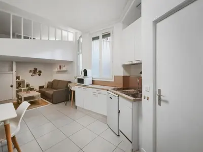 a kitchen with white cabinets and a living room at Studio moderne et douillet au cœur de Nice in Nice