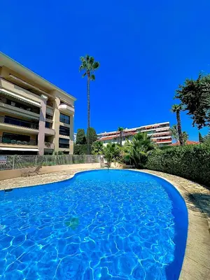 a large blue swimming pool in front of a building at Appartement moderne climatisé avec piscine, terrasse et parking - Proche Promenade des Anglais in Nice