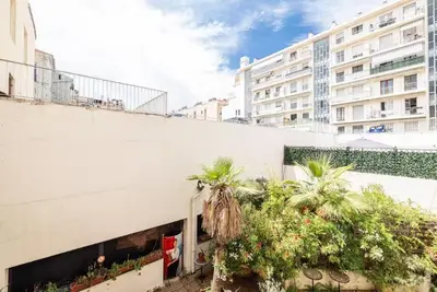 a white building with palm trees next to a building at Au cœur de Nice, Gare à pied et Climatisation in Nice