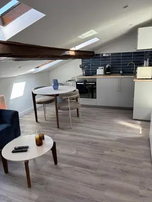 a living room with a table and a kitchen at Cocon lumineux sous les toits de Nice in Nice