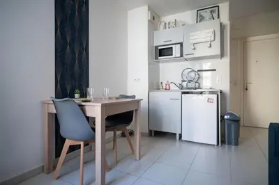 a small kitchen with a table and a refrigerator at Bail mobilité - Beau studio proche tram Saint-Roch in Nice