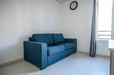 a blue couch in a room with a clock on the wall at Bail mobilité - Beau studio proche tram Saint-Roch in Nice