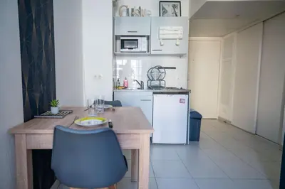 a kitchen with a wooden table and a white refrigerator at Bail mobilité - Beau studio proche tram Saint-Roch in Nice